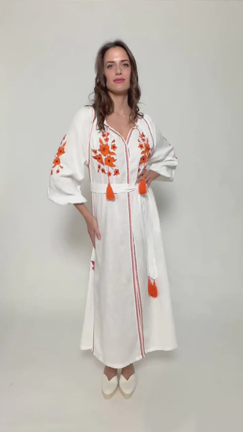 Vestido de lino blanco bordado en naranja con cinturón, pompones y botones de nácar.